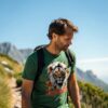 Man hiking in a green T-shirt with a white lion and autumn leaves print, featuring the text “King Energy.”