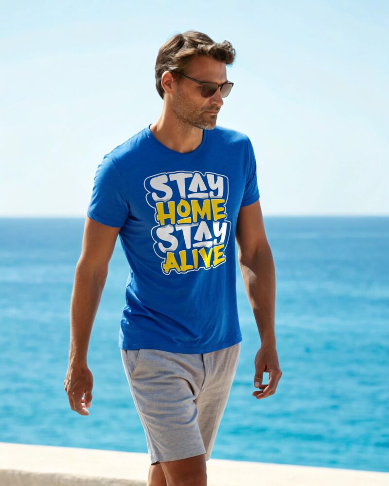A man in a blue T-shirt with the bold slogan "Stay Home Stay Alive" printed in white and yellow letters