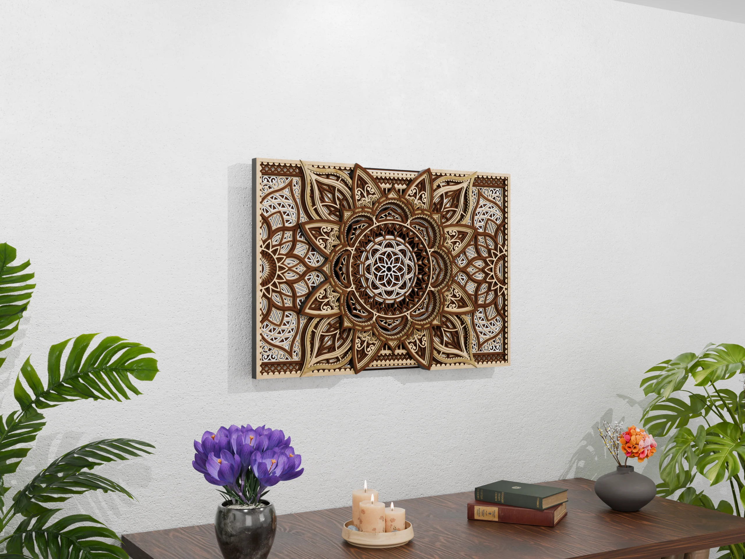 Angled view of a multilayer wooden mandala wall art piece in natural wood tones, displayed above a wooden table with candles, books, flowers, and tropical plants against a light textured wall.