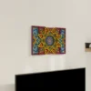 Multilayer Wooden Mandala wall art with a bright symmetrical floral geometric design in yellow, blue, red, and purple, shown on a light wall above a TV from an angled view.