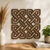 Wooden Celtic knot wall decor with an intricate interwoven geometric design displayed on a neutral wall above a wooden console table.