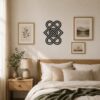 Black Celtic knot wall decor displayed above a wooden bed in a warm neutral bedroom.